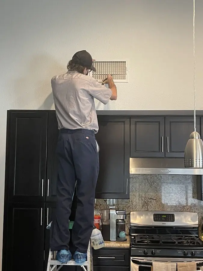Technician inspecting an air vent during HVAC service in East Bradford